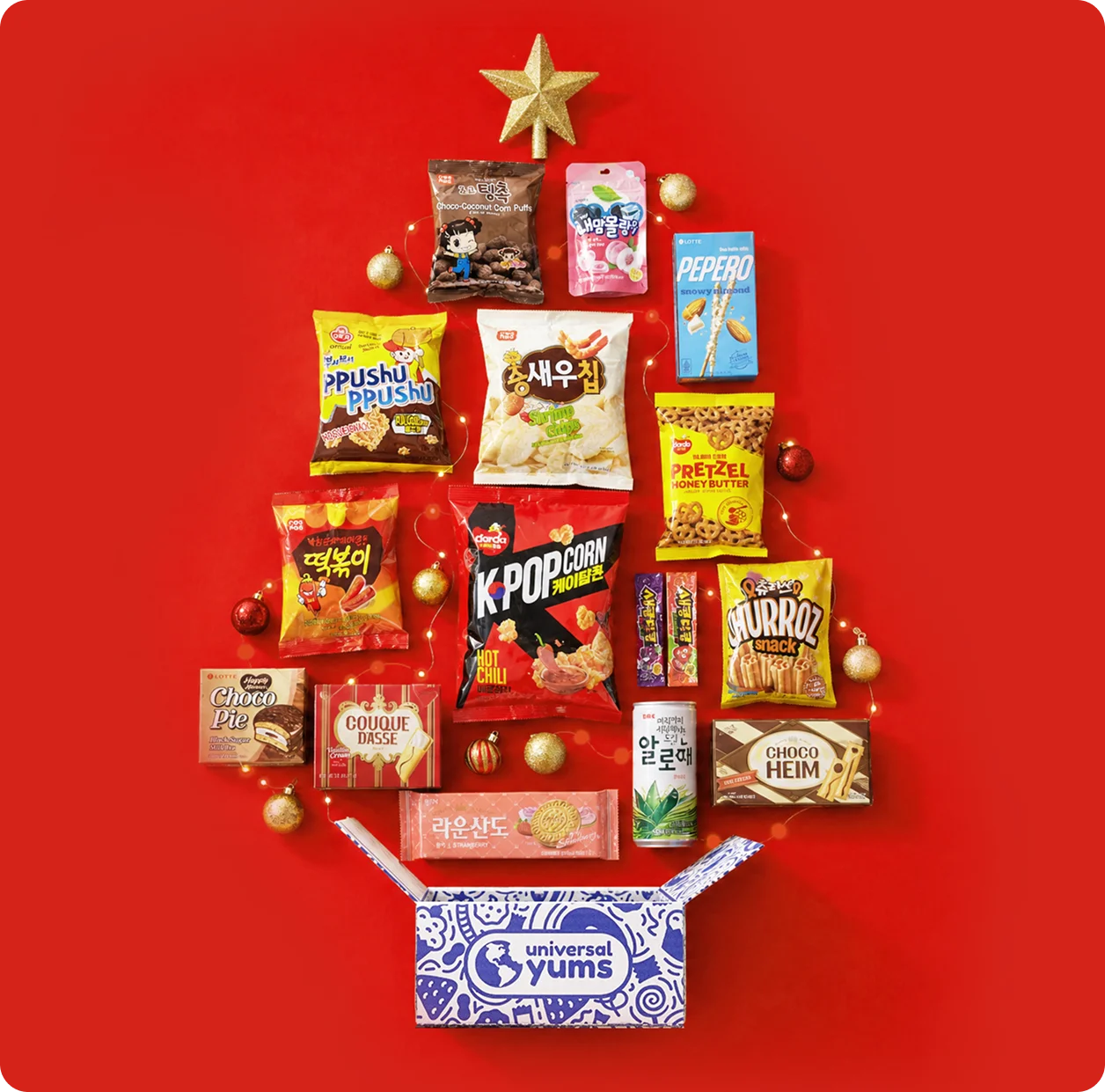 Korean snacks arranged in the shape of a holiday tree above an open Universal Yums box.
